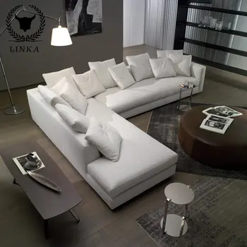 Удобный диван из белой сегментированной ткани в углу современной Г-образной комнаты Изображение